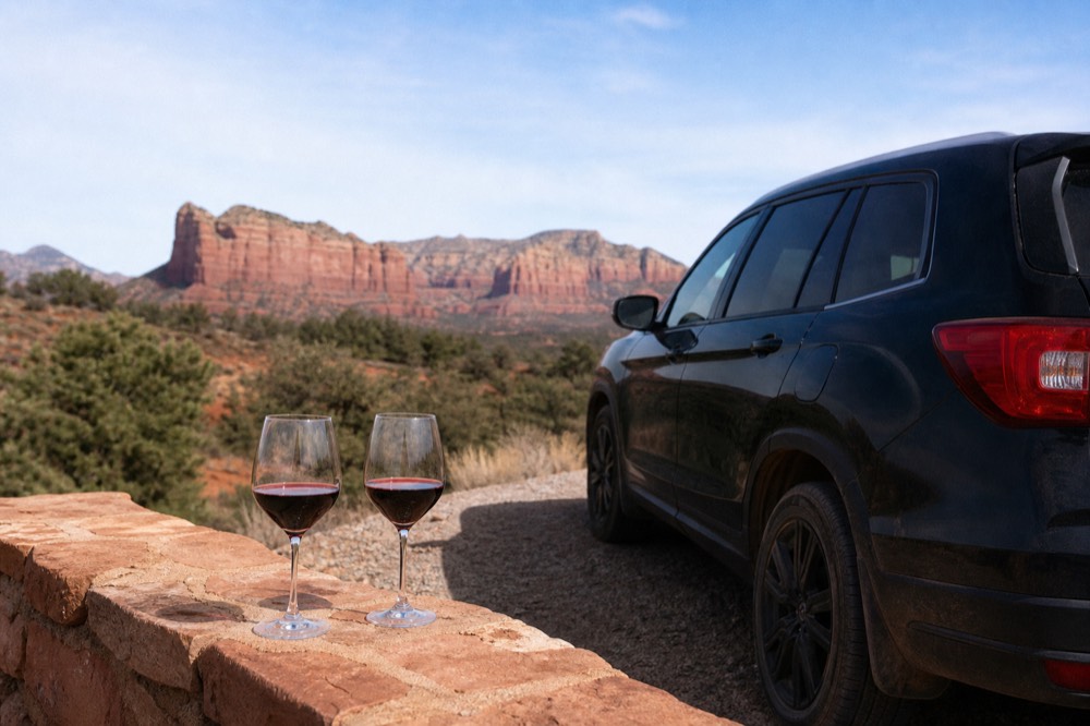 Glasses of red wine set out beside a private tour vehicle at a quiet Verde Valley winery